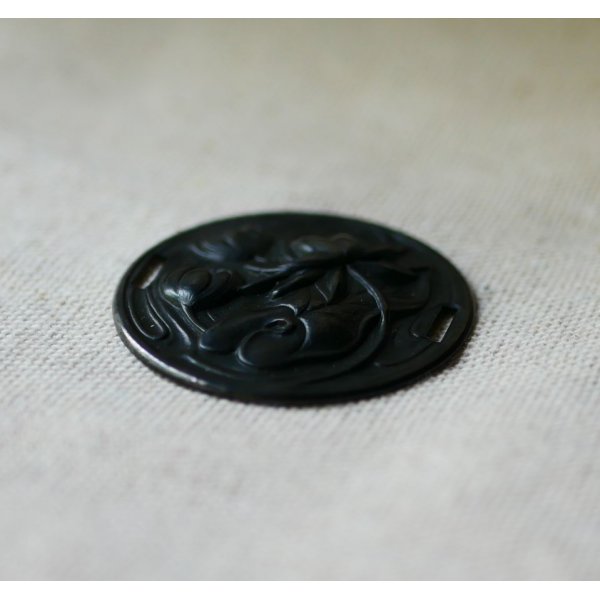 Medaglione a ninfea in metallo nero a rilievo con lacci laterali 